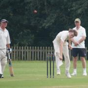 Freddie Fenner bowling for Whimple whilst Mark Burnard looks on